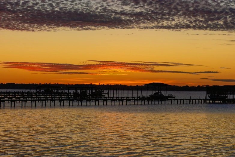 a sunset over a body of water with a pier, by Susy Pilgrim Waters, hurufiyya, fan favorite, panorama, graphic print, manly
