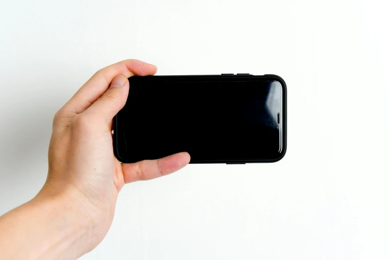 a person holding a cell phone in their hand, a picture, rounded corners, black plastic, turned back to camera, f / 1 1. 0
