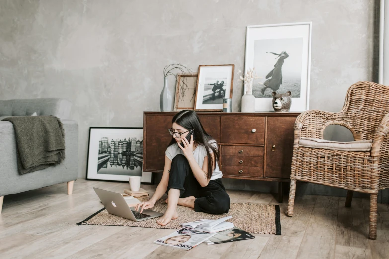 a woman sitting on the floor using a laptop, a picture, trending on pexels, visual art, furniture around, girl making a phone call, girl with glasses, vintage photo