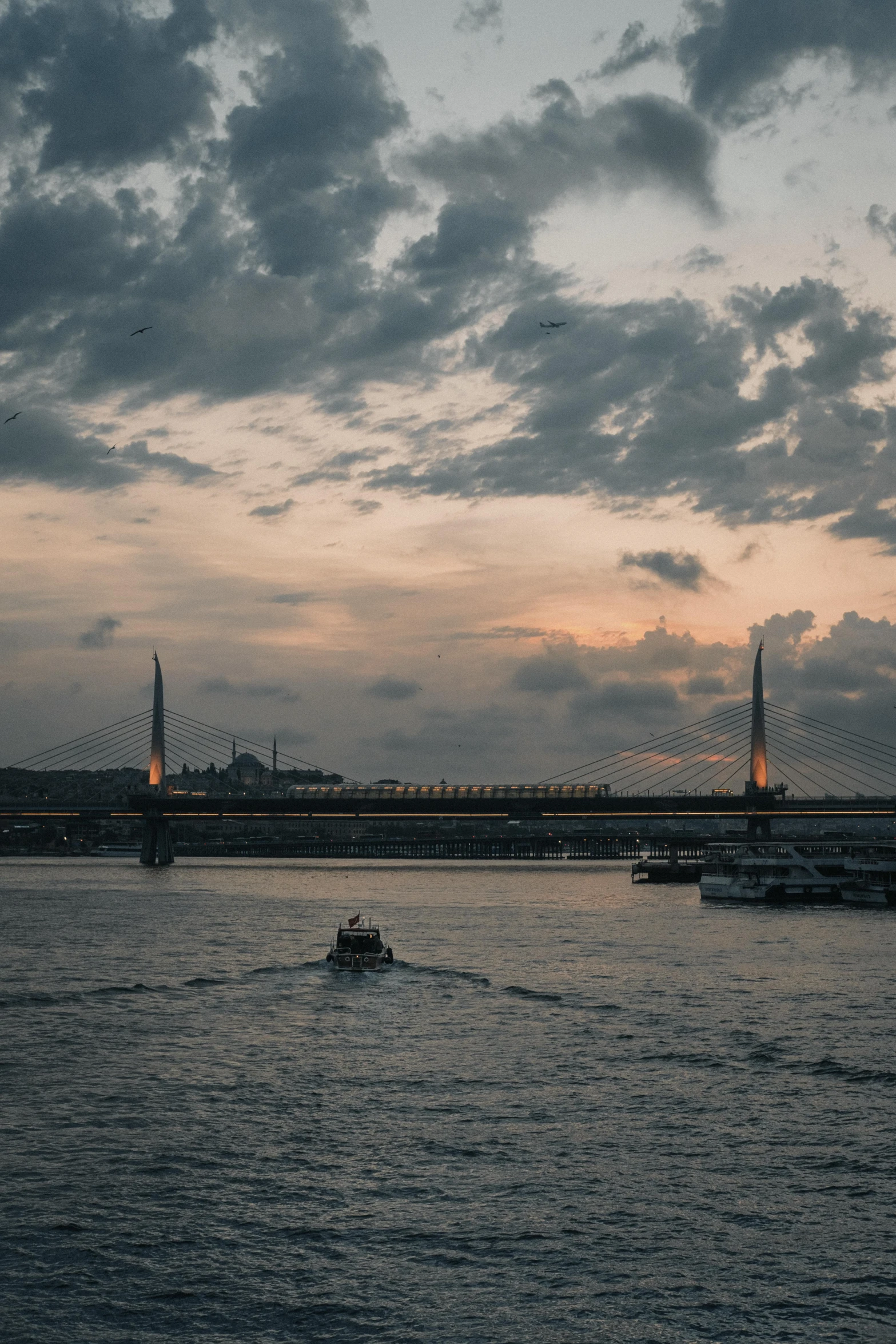 a couple of boats that are in the water, by Cafer Bater, pexels contest winner, hurufiyya, soaring towers and bridges, overcast dusk, sunset time, spires