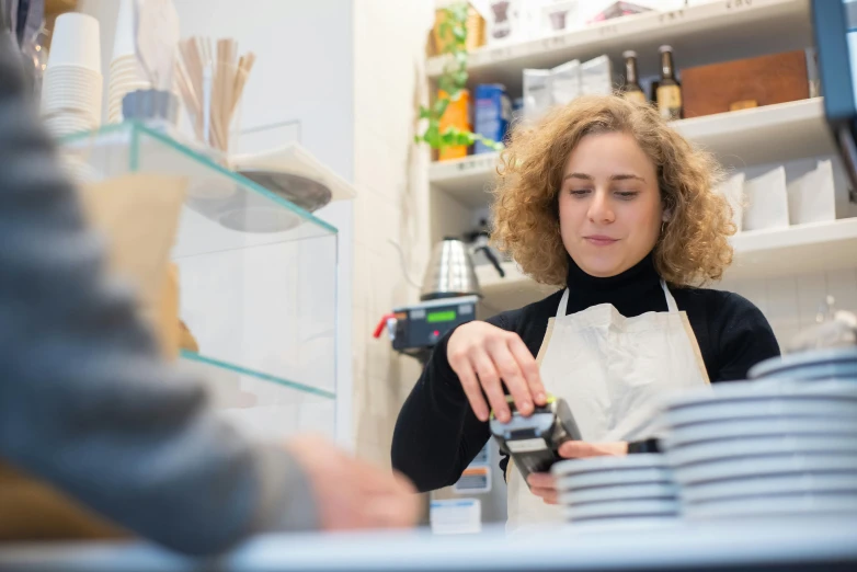 a woman is working in a coffee shop, pexels contest winner, private press, cash register, thumbnail, unedited, caucasian