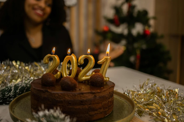 a woman sitting in front of a cake with candles on it, trending on pexels, golden number, wearing festive clothing, avatar image, portlet photo