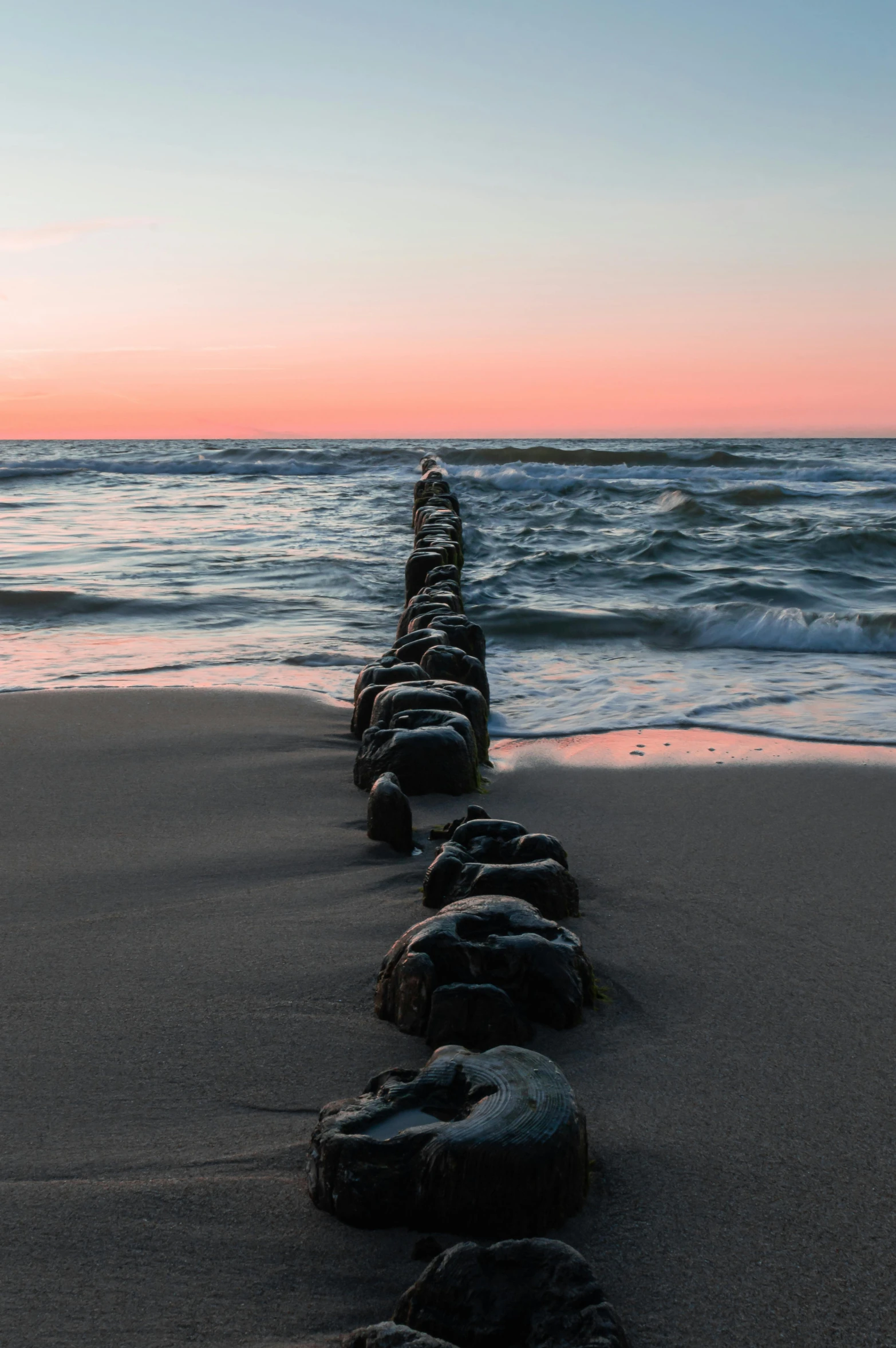 a long line of rocks sitting on top of a sandy beach, pipelines, infinite dawn, ignant, sea line