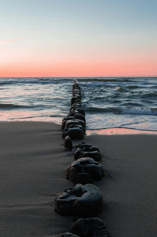 a long line of rocks sitting on top of a sandy beach, pipelines, infinite dawn, ignant, sea line