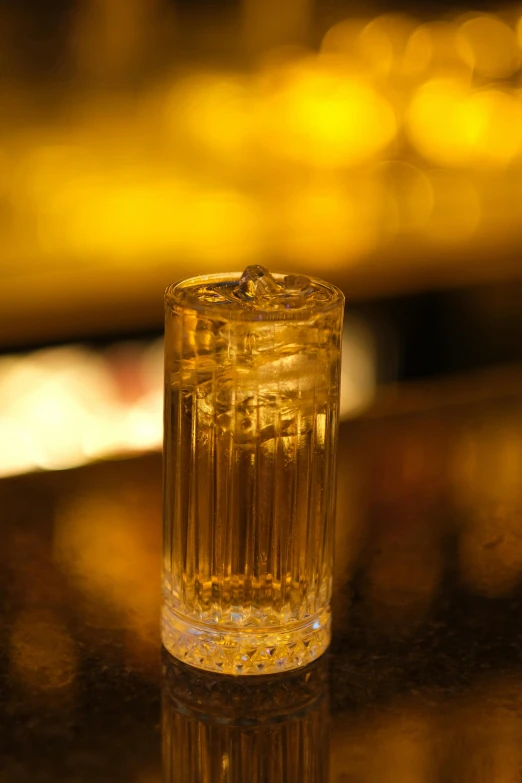 a close up of a glass of water on a table, inspired by Hugo Kārlis Grotuss, trending on reddit, sitting at the bar, gold-shot, tall iced tea glass, monaco