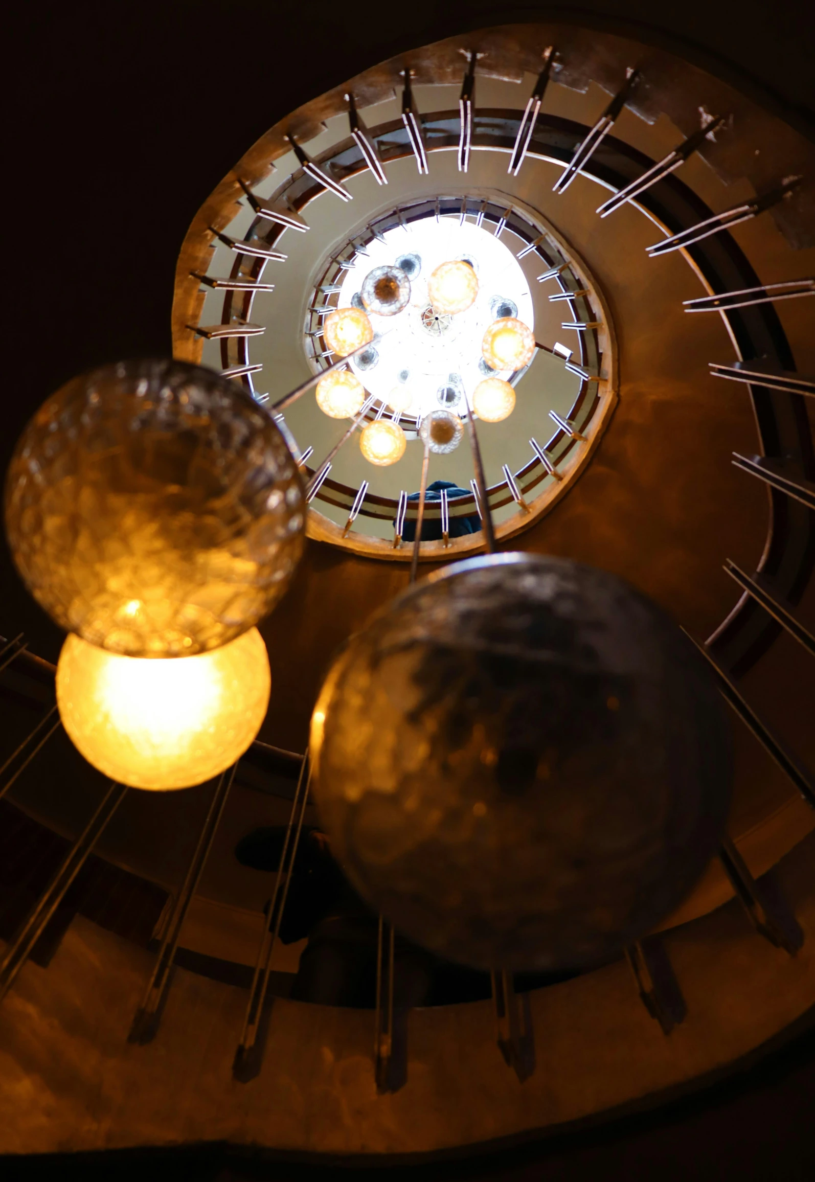 a view from the top of a spiral staircase, by David Donaldson, light and space, hanging lanterns, sphere, from below, warm lights