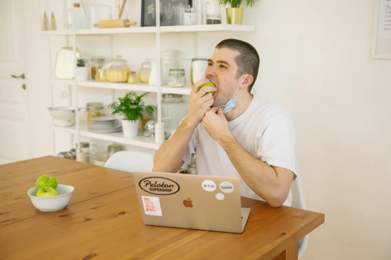 a man sitting at a table eating an apple, pexels contest winner, sitting in front of computer, liam, side fed, having a snack