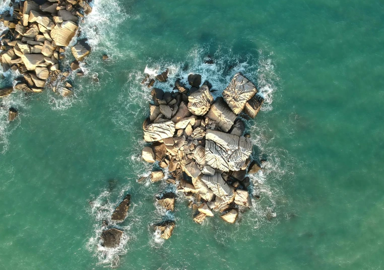 a group of rocks sitting on top of a body of water, arial shot, epic 3 d omolu, high res 8k, ((rocks))