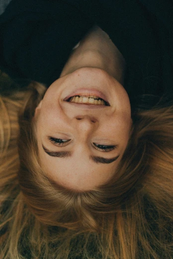 a woman laying on top of a lush green field, a picture, by Niko Henrichon, trending on pexels, symmetrical face happy, human head with blonde hair, high angle closeup portrait, as she looks up at the ceiling