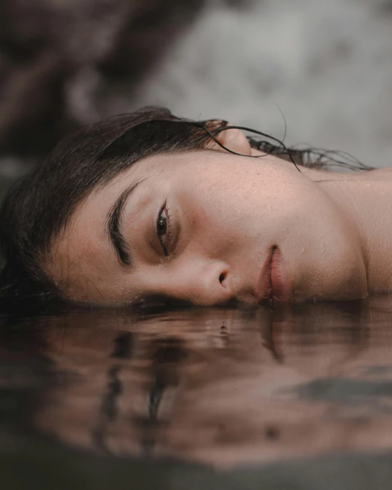 a woman laying down in a body of water, inspired by Elsa Bleda, trending on pexels, renaissance, androgynous face, lgbtq, teenage girl, sad face