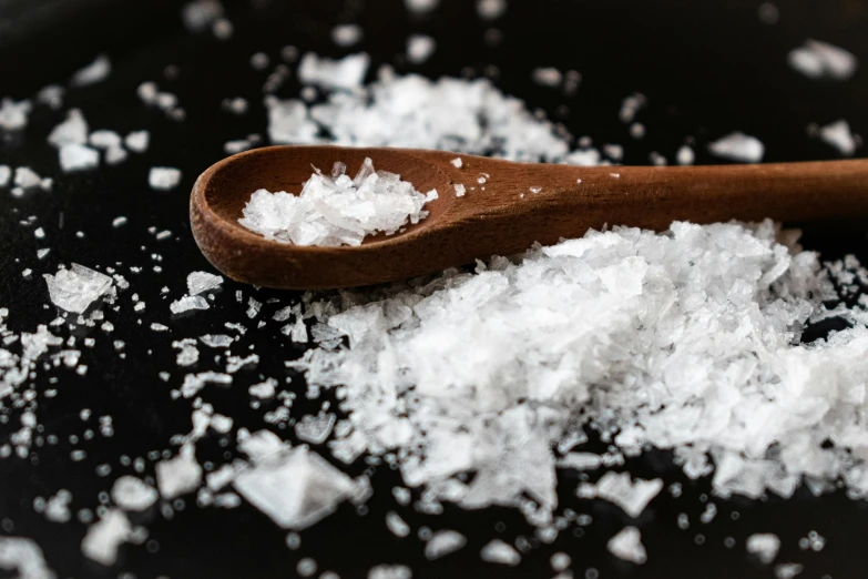 a wooden spoon sitting on top of a pile of salt, a portrait, unsplash, on black background, 🍸🍋, digital image, contain