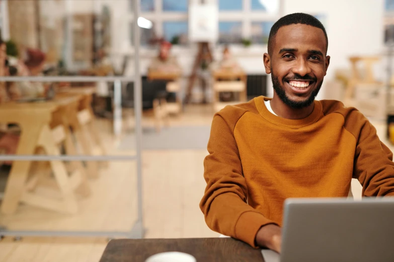 a man sitting in front of a laptop computer, inspired by Afewerk Tekle, trending on pexels, hurufiyya, smiling confidently, thumbnail, midshot single subject, commercial