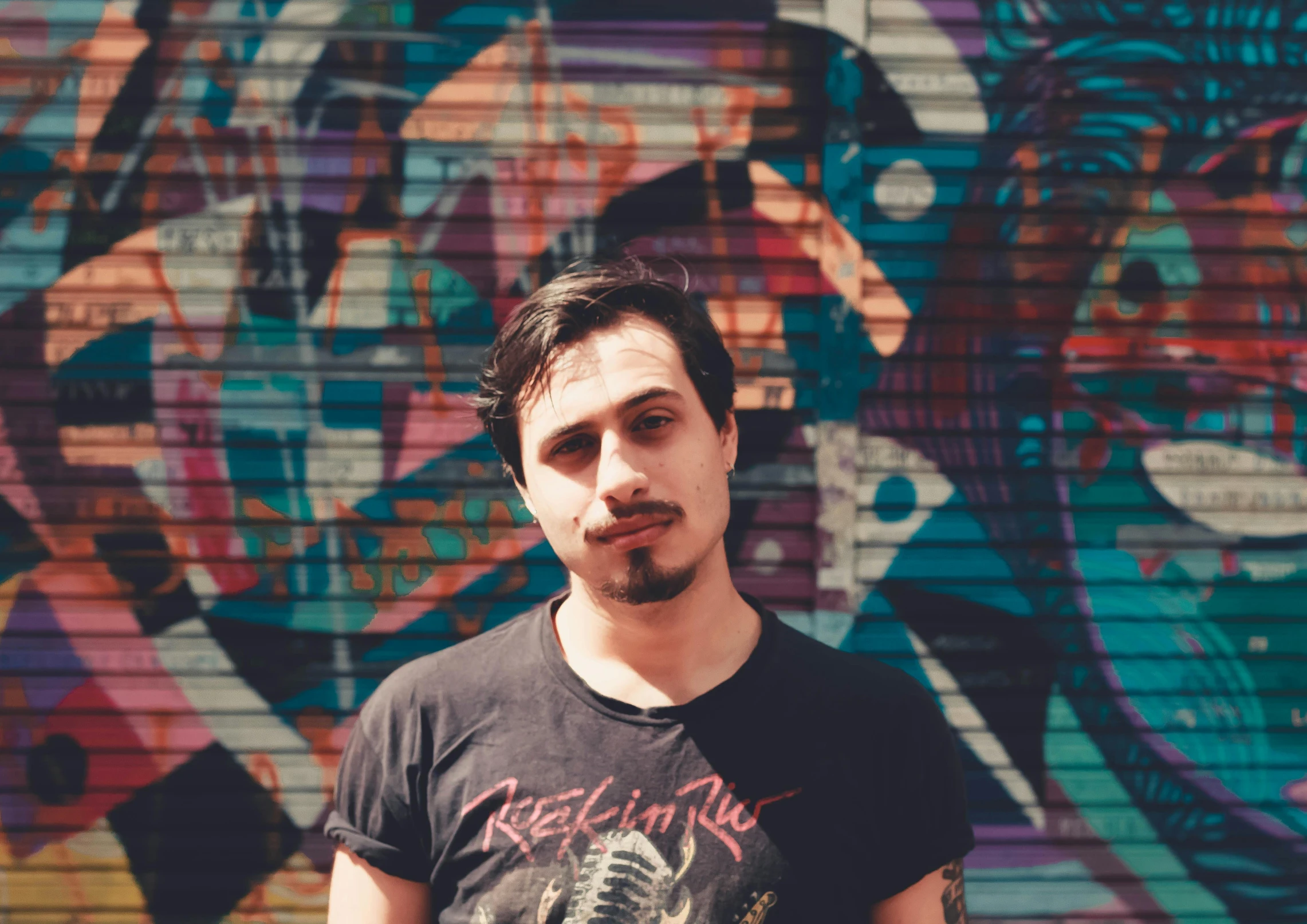 a man standing in front of a graffiti covered wall, a portrait, inspired by Elsa Bleda, black lips, promotional image, profile image, discord profile picture