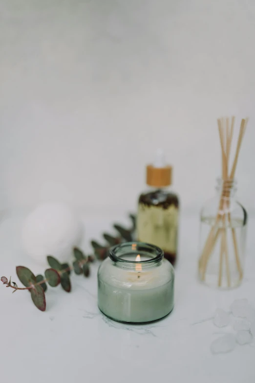 a candle that is sitting on a table, various items, bubble bath, on grey background, over-shoulder shot