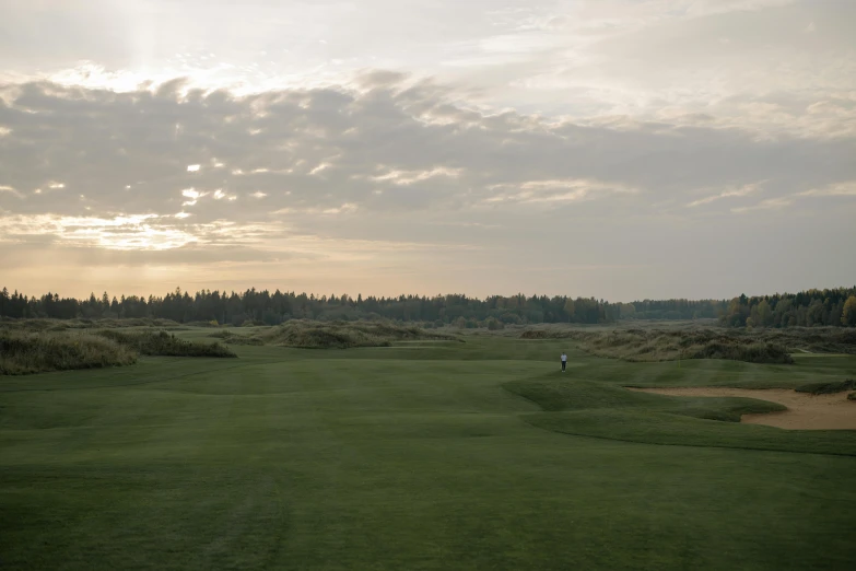 a man standing on top of a green field, wrx golf, last light, haida, distant photo