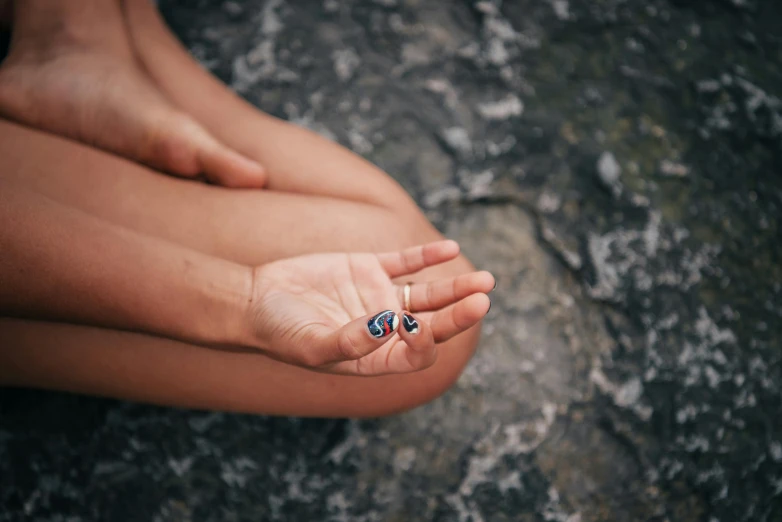 a close up of a person holding something in their hand, by Emma Andijewska, unsplash, lapis lazuli, barefoot, paua shell, tiny girl looking on