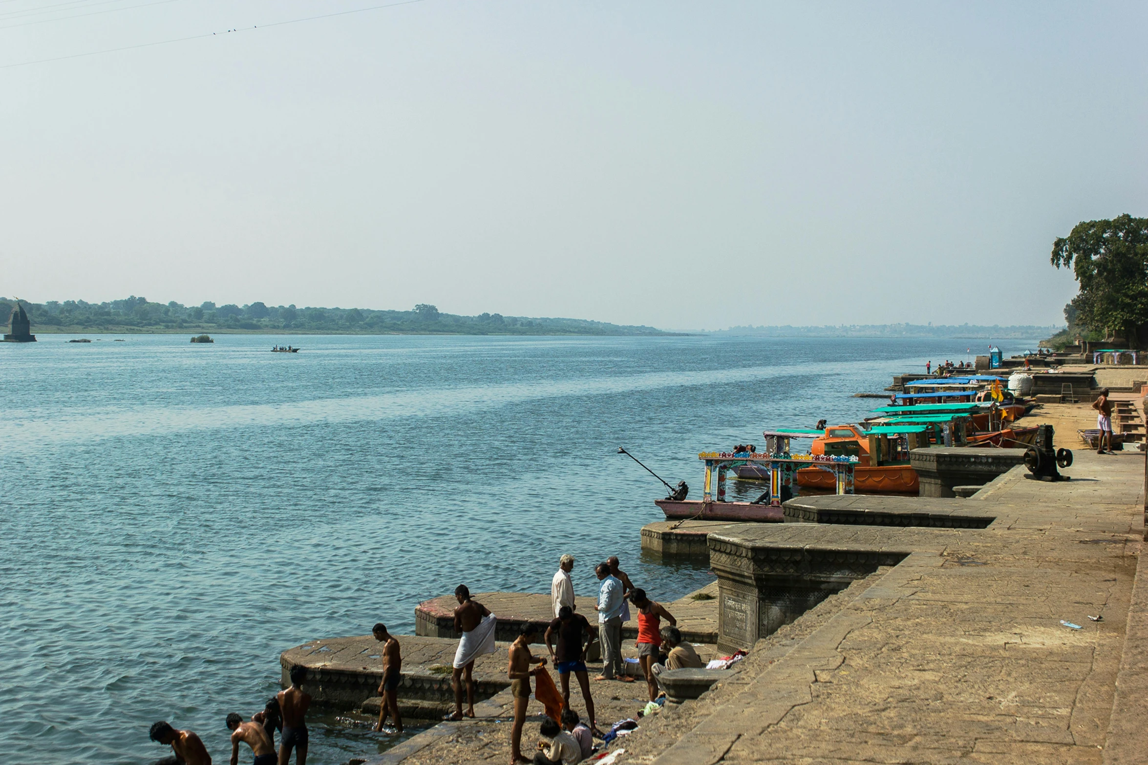 a group of people standing next to a body of water, happening, indore, near a jetty, fishing town, listing image