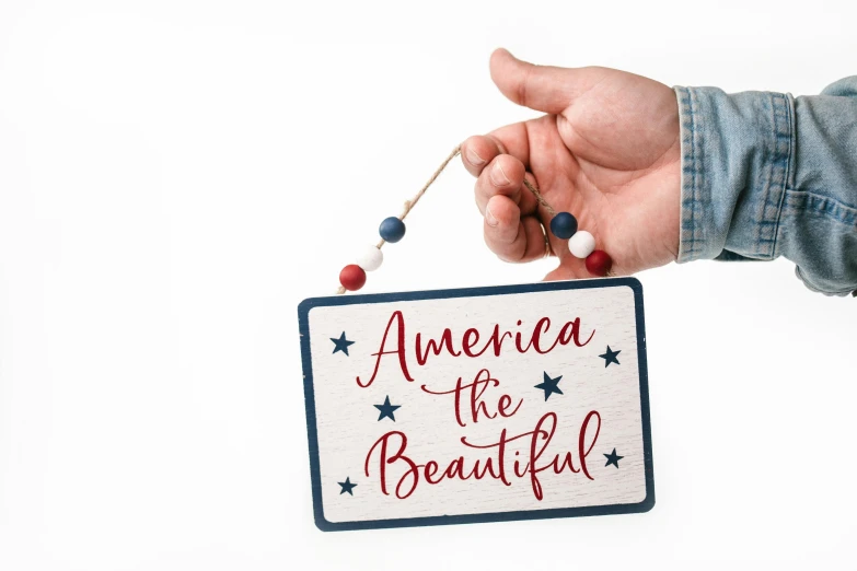 a person holding a sign that says america is beautiful, american romanticism, miniature product photo, hanging, set against a white background, brilliantly coloured