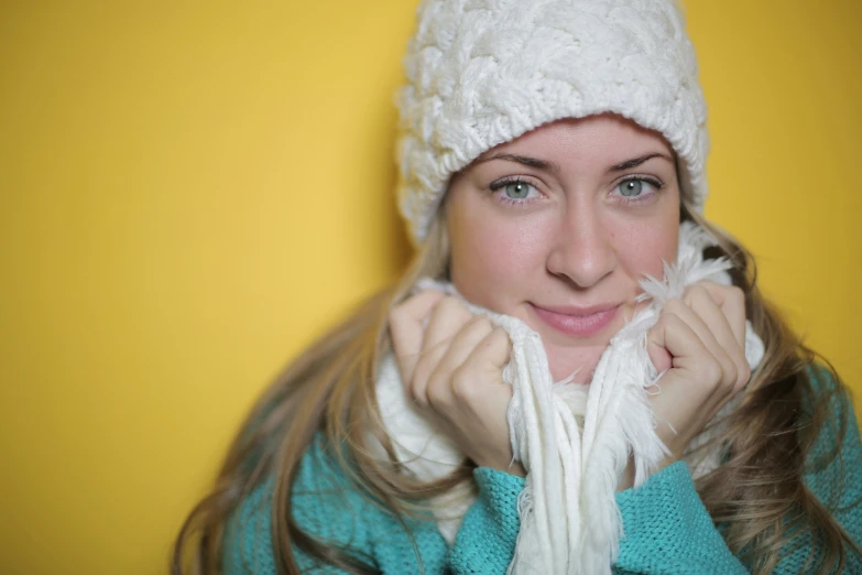 a close up of a person wearing a hat and scarf, yellow backdrop, cold snowy, indoor picture, portrait image