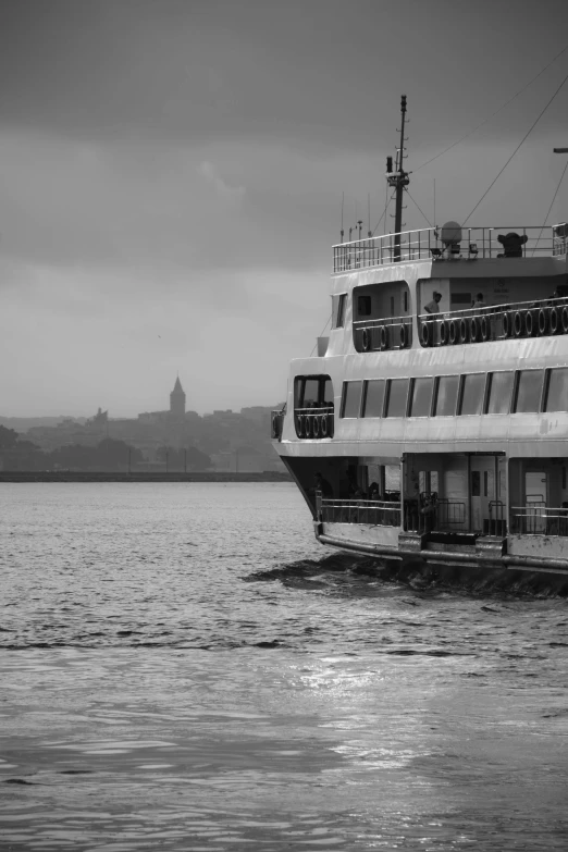 a large boat floating on top of a body of water, a black and white photo, by Tamas Galambos, flickr, 256x256, castle in background, rainy evening, harbour in background