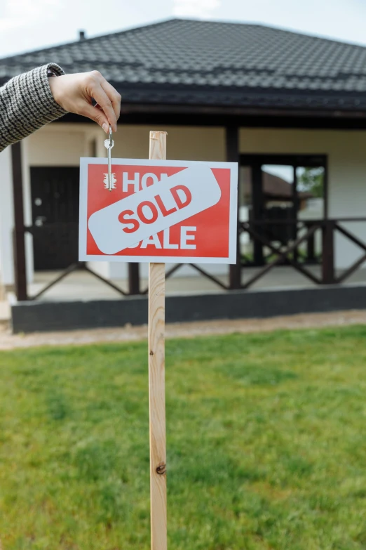 a woman holding a sold sign in front of a house, a photo, pexels, square, holding a crowbar, a labeled, land