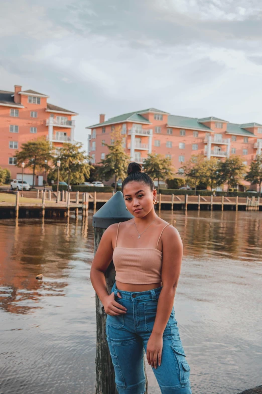 a woman standing on a dock next to a body of water, in savannah, mixed race woman, profile image, thicc