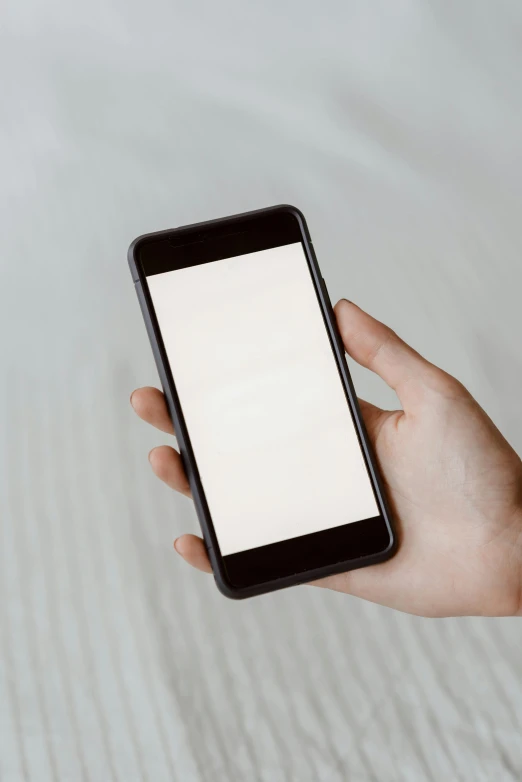 a person holding a smart phone with a white screen, by Carey Morris, pexels, square, screensaver, on my bed, gradient brown to white