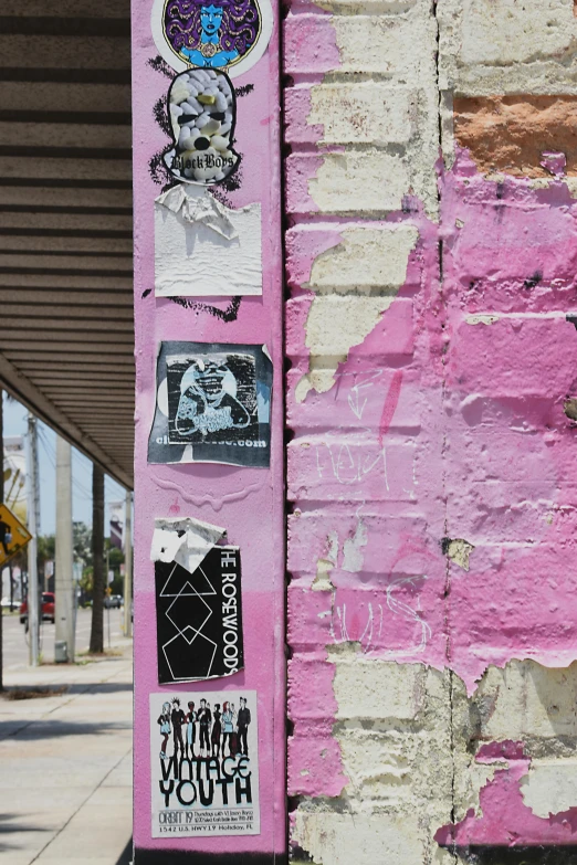 a pink pole with a bunch of stickers on it, poster art, by Lee Loughridge, graffiti, los angelos, rundown buildings, non-binary, ( collage )