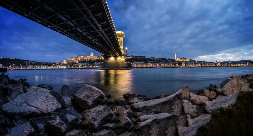 a bridge over a body of water under a cloudy sky, by Tom Wänerstrand, pexels contest winner, budapest, blue hour, thumbnail, slide show