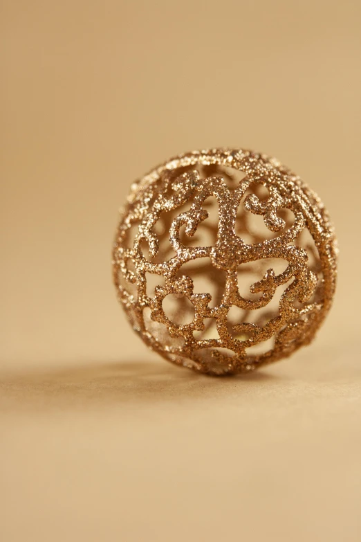 a pair of earrings sitting on top of a table, a stipple, inspired by Matteo Pérez, arabesque, 2 8 mm macro photo, ball, gold paint, rose gold