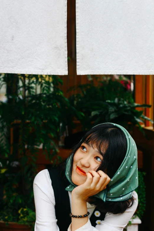 a woman sitting at a table with an umbrella over her head, inspired by Kim Jeong-hui, unsplash, curtain bangs, green hood, hijab, jaeyeon nam