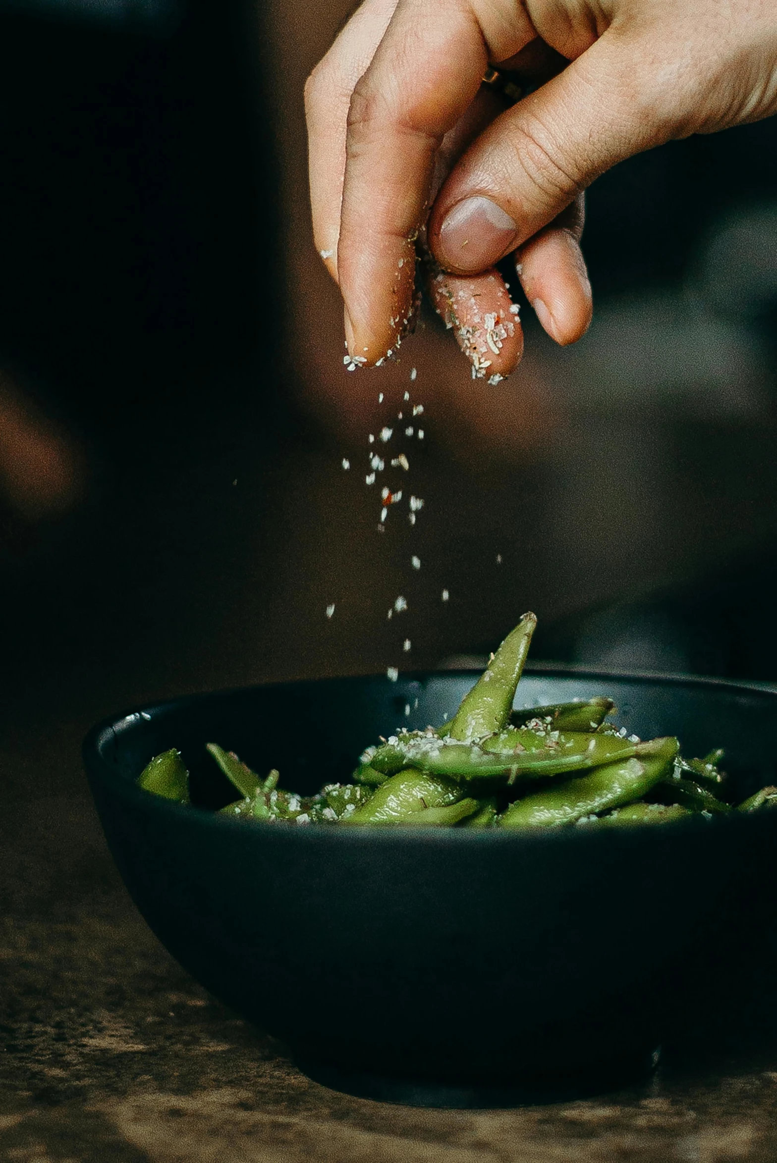 a person sprinkling salt onto a bowl of food, jack and the bean stalk, sage, dark, no cropping