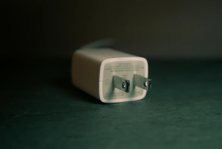 a white charger sitting on top of a green table, a picture, unsplash, capacitors, dimly lit, square, ((sharp focus))