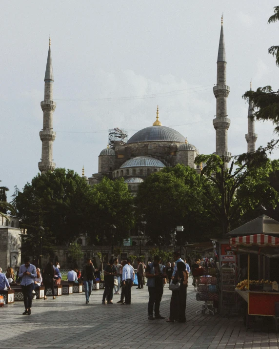 a group of people standing in front of a building, by Ismail Acar, pexels contest winner, hurufiyya, black domes and spires, park in background, marble columns in background, lgbtq