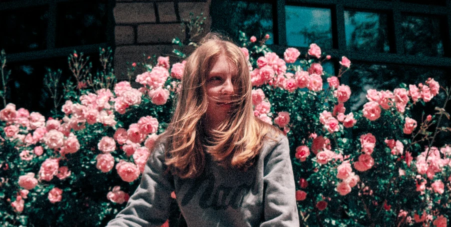 a woman sitting on top of a red fire hydrant, an album cover, tumblr, photorealism, wearing a hoodie and flowers, petra collins and mc. escher, sitting in the rose garden, a still of a happy