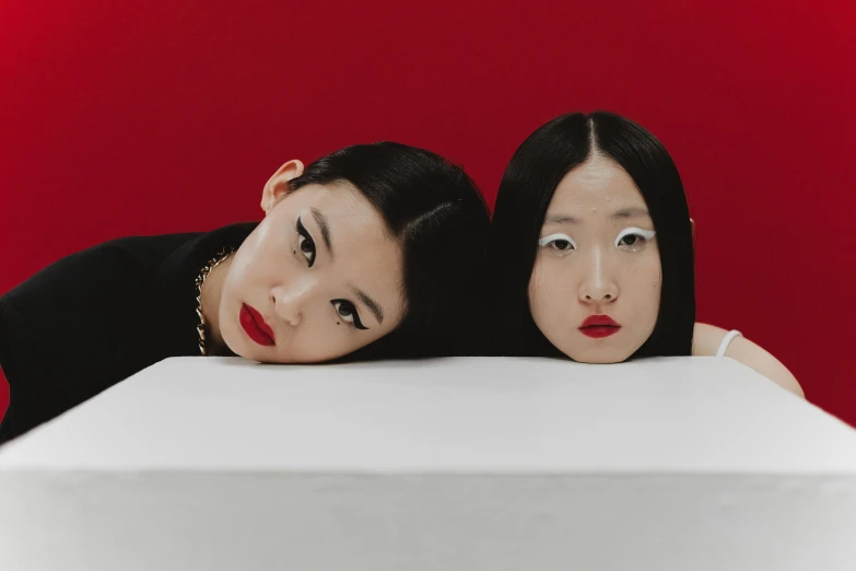 a couple of women sitting next to each other, an album cover, inspired by Wang Duo, red contact lenses, asian descent, looking away from viewer, sephora