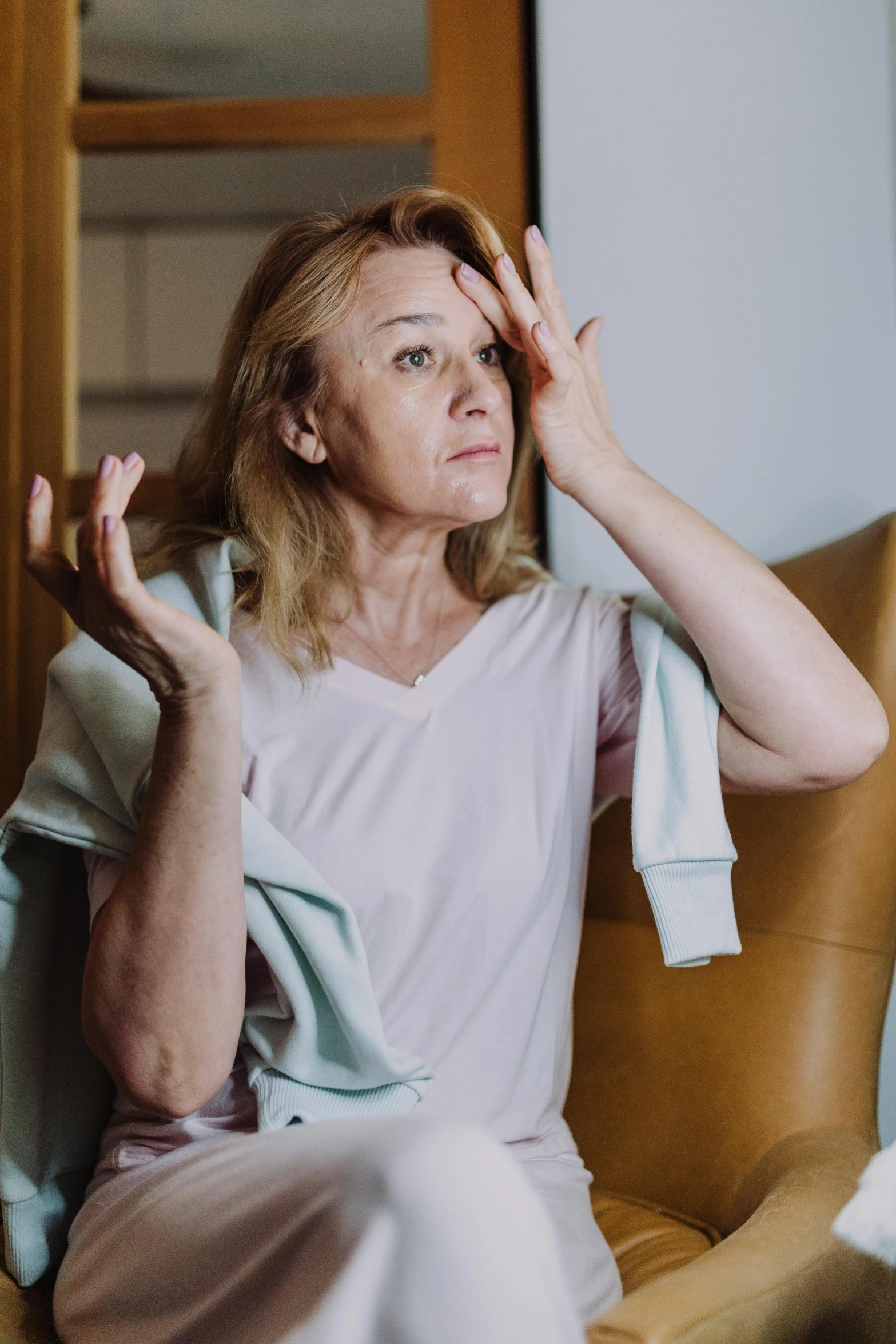 a woman sitting in a chair with a towel on her head, a portrait, trending on unsplash, shrugging arms, looking in mirror at older self, as well as scratches, drunk woman