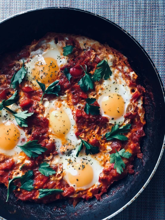 a pan filled with eggs on top of a table, by Adam Rex, hurufiyya, tomato sauce, genzoman, breakfast, high quality product image”