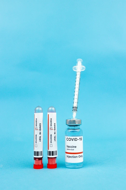 two vials sitting next to each other on a blue background, a picture, shutterstock, syringe, label, covid, set against a white background