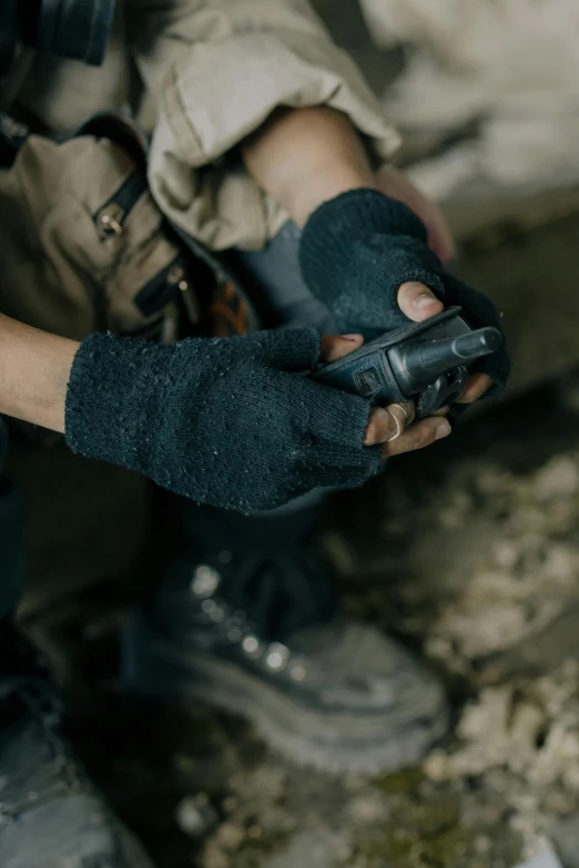 a close up of a person holding a cell phone, gloves, rugged black clothes, exploring, holding pdw