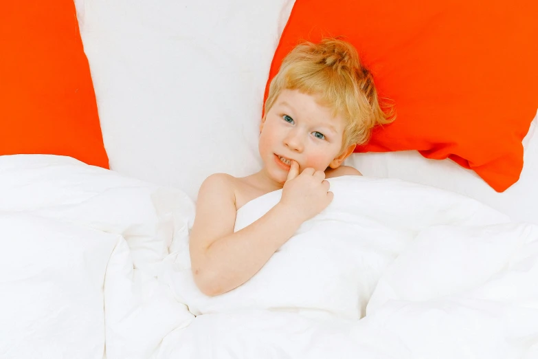 a little boy that is laying in a bed, by Ruth Simpson, pexels, white and orange, sheet, red cheeks, thumbnail