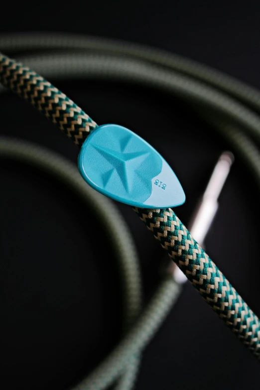 a close up of a cord with a guitar pick on it, teal electricity, full product shot, technical detail, spire