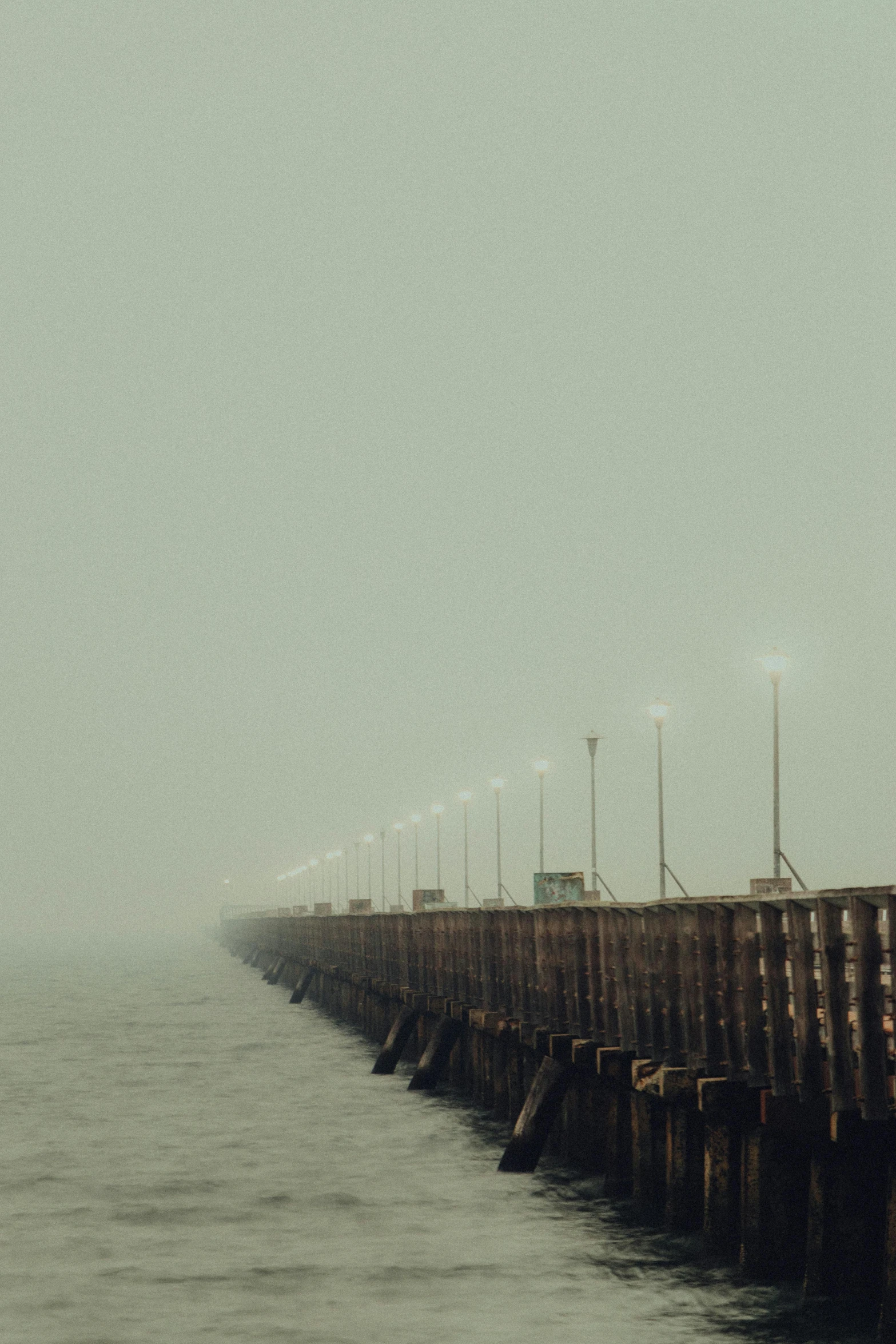 a long wooden pier on a foggy day, an album cover, inspired by Elsa Bleda, search lights, ignant, shot on sony a 7, california;