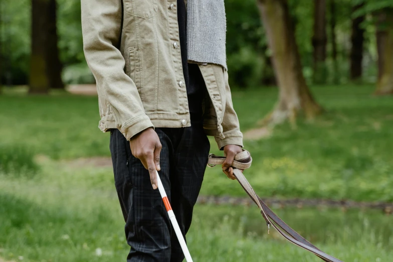 a man walking a dog on a leash, by Helen Stevenson, unsplash, young male with walking stick, in the park, cast, blind brown man
