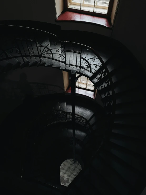 a spiral staircase in a dark room next to a window, pexels contest winner, low quality photo, camera looking down into the maw, dark shades, two stories