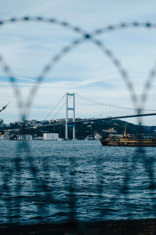 a ship in a body of water with a bridge in the background, by irakli nadar, pexels contest winner, hurufiyya, behind bars, banner, istanbul, slide show