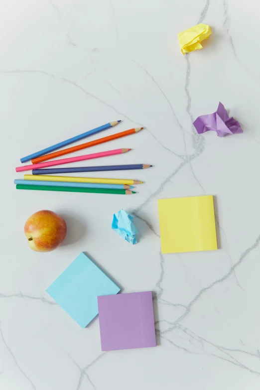 a bunch of colored pencils sitting on top of a table, a still life, by Nicolette Macnamara, pexels, square shapes, while marble, apple, blank paper