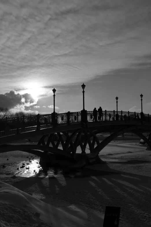 a black and white photo of a bridge, a black and white photo, inspired by Vasily Perov, romanticism, sun set, walking on ice, in moscow centre, ( ( photograph ) )