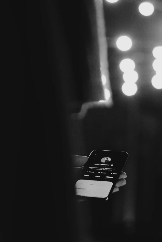 a black and white photo of a person holding a cell phone, trending on spotify, in the spotlight, ( ( theatrical ) ), uploaded