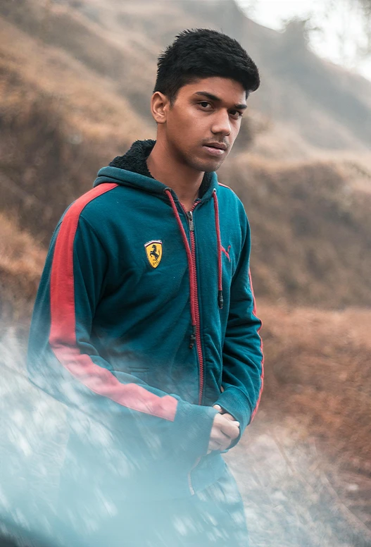 a man that is standing in the dirt, a colorized photo, pexels contest winner, ferrari logo on it's chest, blue hoodie, indian, mountainside